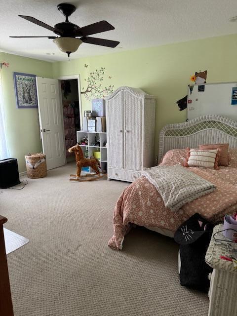 carpeted bedroom featuring ceiling fan and a textured ceiling