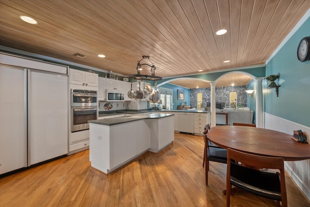 kitchen with decorative light fixtures, stainless steel appliances, kitchen peninsula, and white cabinets