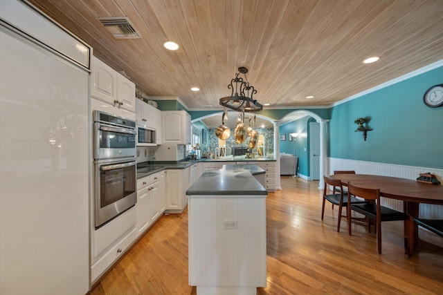 kitchen with crown molding, appliances with stainless steel finishes, hanging light fixtures, and white cabinets