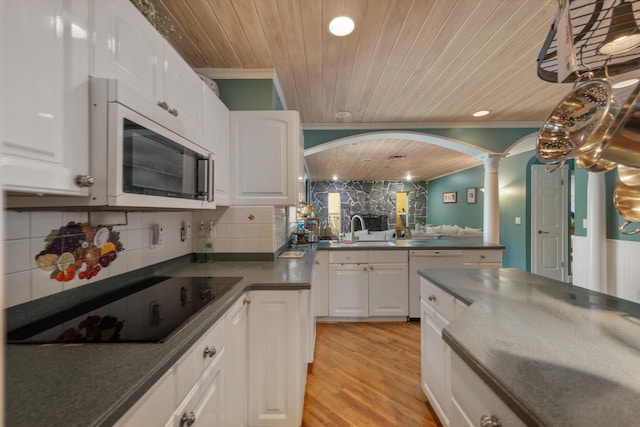 kitchen featuring black electric stovetop, sink, and white cabinets