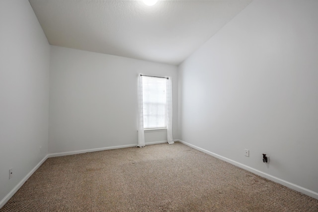 carpeted spare room with lofted ceiling