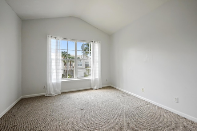 carpeted empty room with lofted ceiling