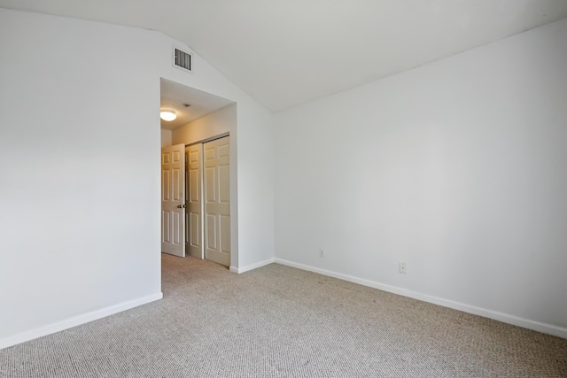 carpeted empty room featuring lofted ceiling