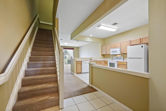 kitchen featuring white appliances, kitchen peninsula, and light brown cabinets