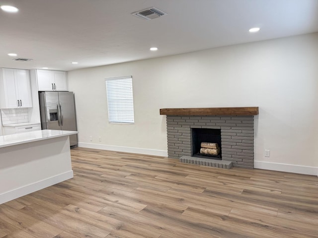 unfurnished living room with a fireplace and light hardwood / wood-style floors