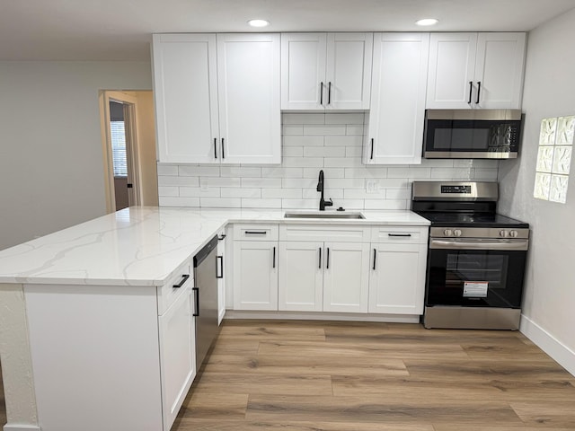 kitchen with white cabinetry, sink, kitchen peninsula, and appliances with stainless steel finishes