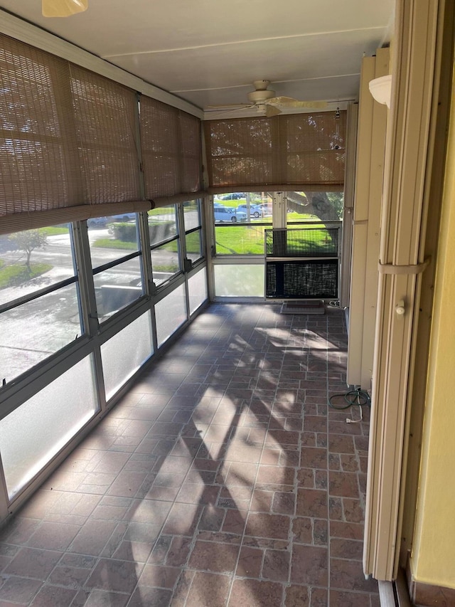 unfurnished sunroom featuring a ceiling fan