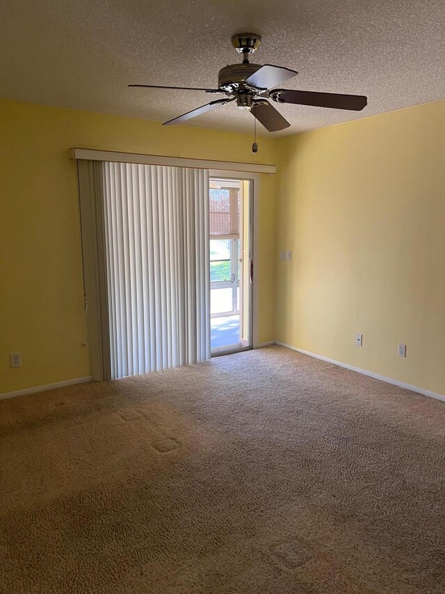 carpeted empty room featuring a textured ceiling, baseboards, and a ceiling fan