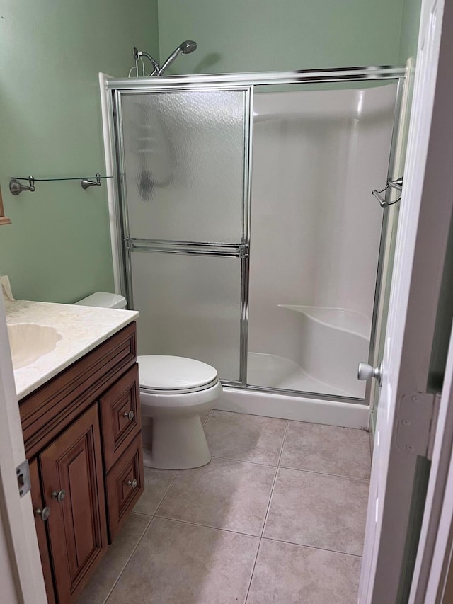 bathroom with vanity, tile patterned floors, toilet, and a stall shower