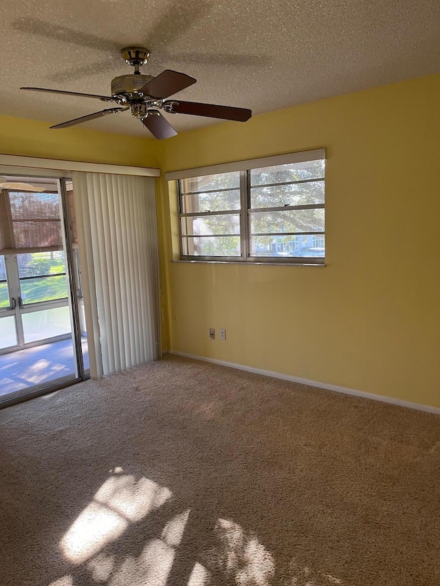 carpeted empty room with a ceiling fan, baseboards, and a textured ceiling