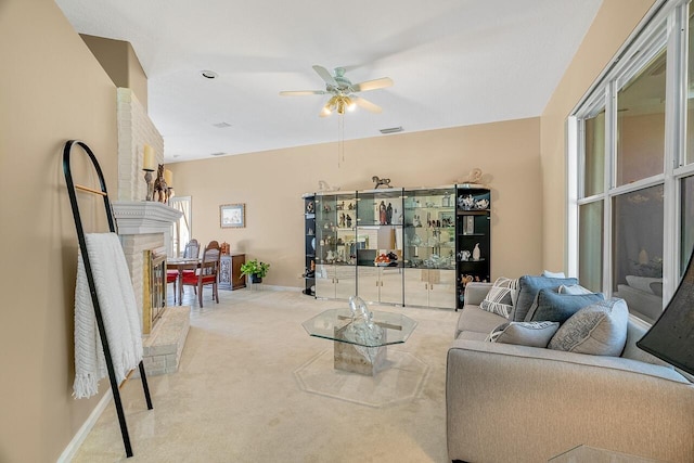 living room featuring ceiling fan, a brick fireplace, and light colored carpet