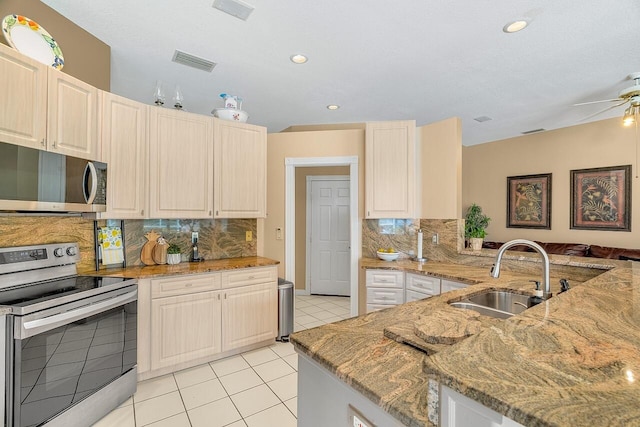 kitchen featuring kitchen peninsula, sink, light tile patterned floors, light stone countertops, and stainless steel appliances