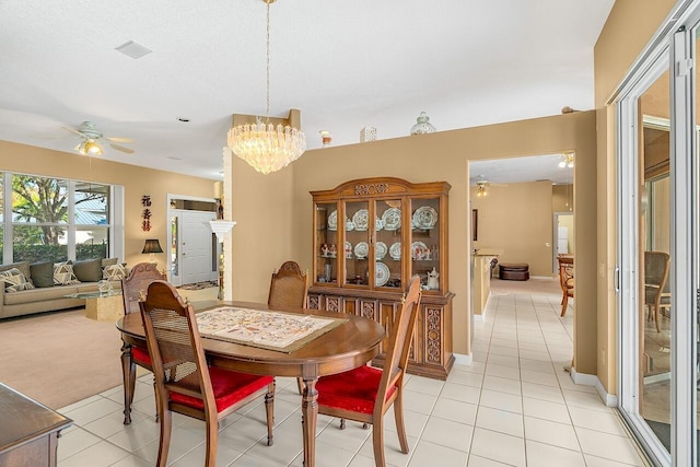 tiled dining area with ceiling fan with notable chandelier