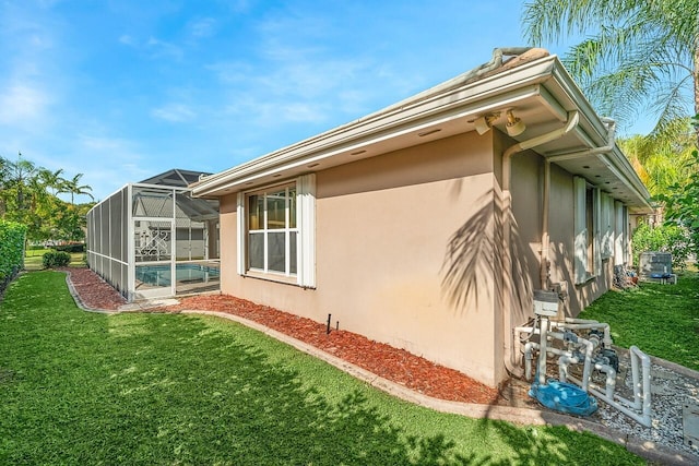 view of side of home with glass enclosure and a lawn