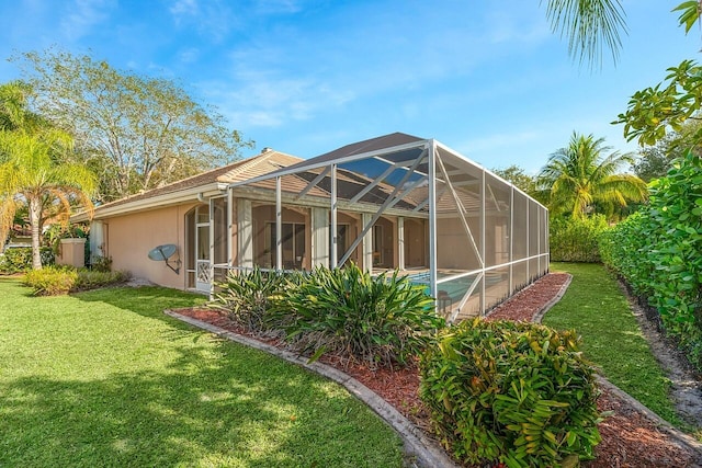 back of property featuring glass enclosure and a lawn