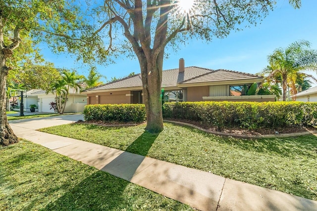 ranch-style home featuring a garage and a front lawn