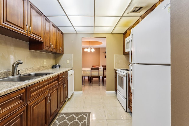 kitchen featuring white appliances, a paneled ceiling, sink, backsplash, and a chandelier