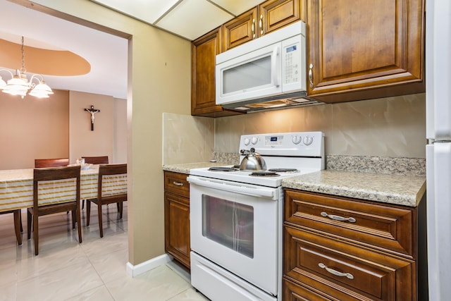 kitchen with white appliances, hanging light fixtures, a notable chandelier, light stone counters, and light tile patterned floors