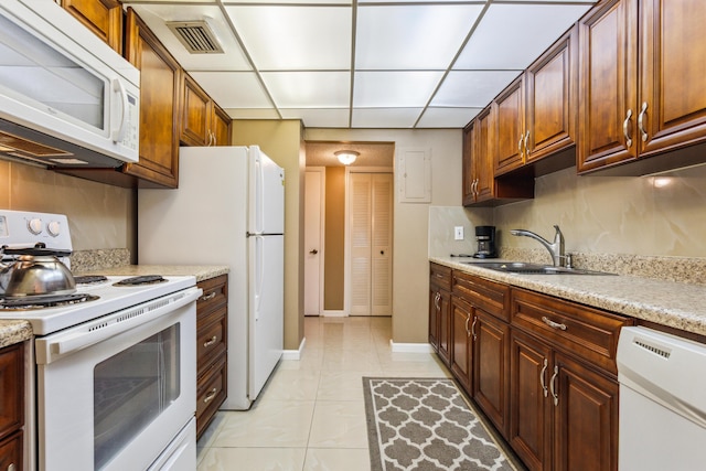 kitchen featuring sink, white appliances, a drop ceiling, and light tile patterned floors