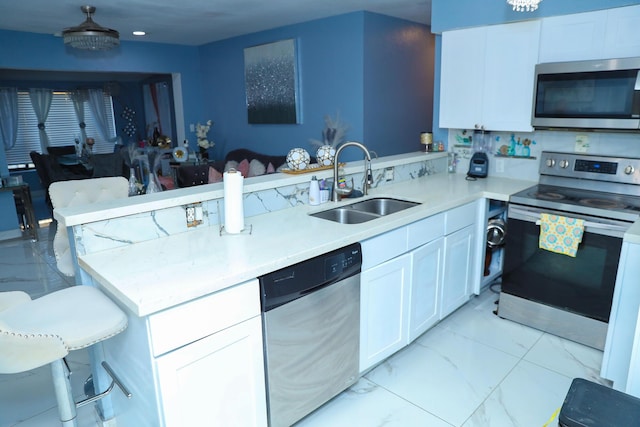 kitchen with sink, stainless steel appliances, kitchen peninsula, and white cabinets