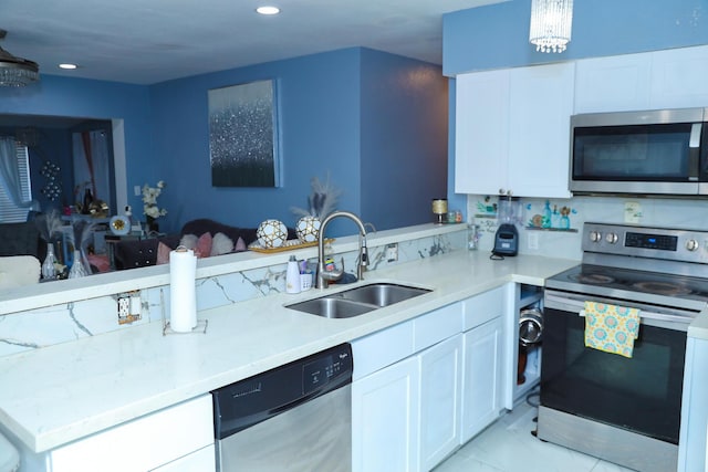 kitchen with white cabinetry, stainless steel appliances, kitchen peninsula, and sink