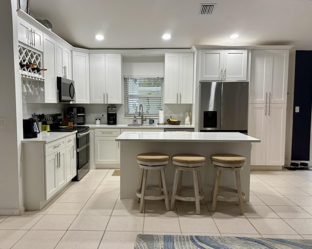 kitchen with sink, white cabinetry, appliances with stainless steel finishes, and a center island