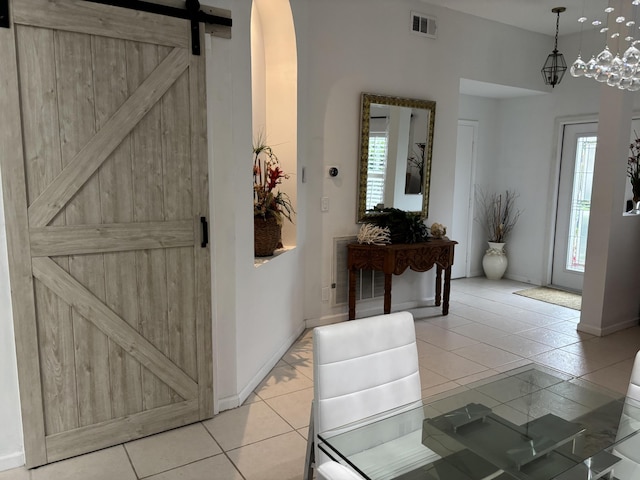 foyer entrance with plenty of natural light, light tile patterned floors, and a barn door