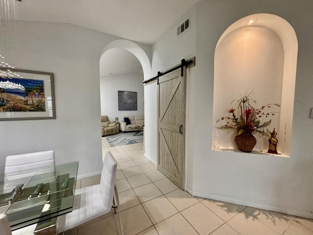 corridor with light tile patterned flooring and a barn door