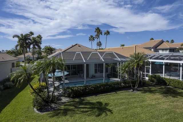 rear view of house with a yard, a patio area, and glass enclosure