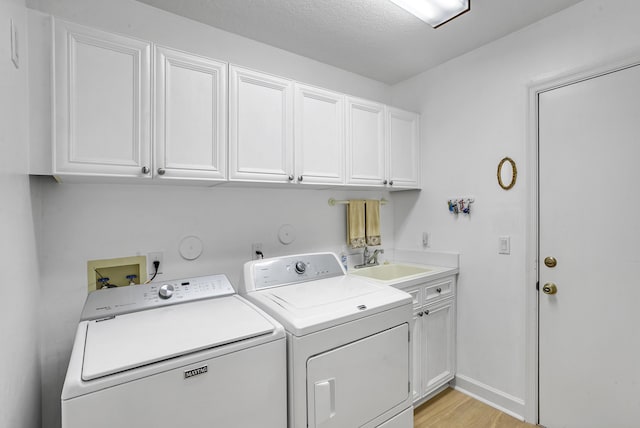 washroom featuring light hardwood / wood-style floors, cabinets, washer and clothes dryer, and sink