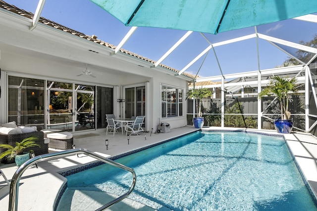 view of swimming pool featuring ceiling fan, an outdoor hangout area, glass enclosure, and a patio area