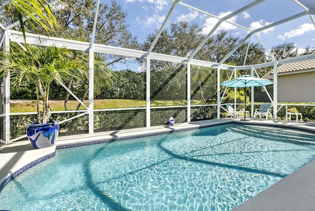 view of swimming pool featuring a patio area and glass enclosure