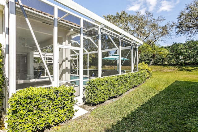 exterior space featuring a lawn and glass enclosure