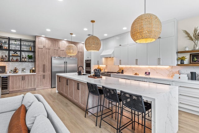 kitchen featuring white cabinetry, hanging light fixtures, stainless steel appliances, and a spacious island