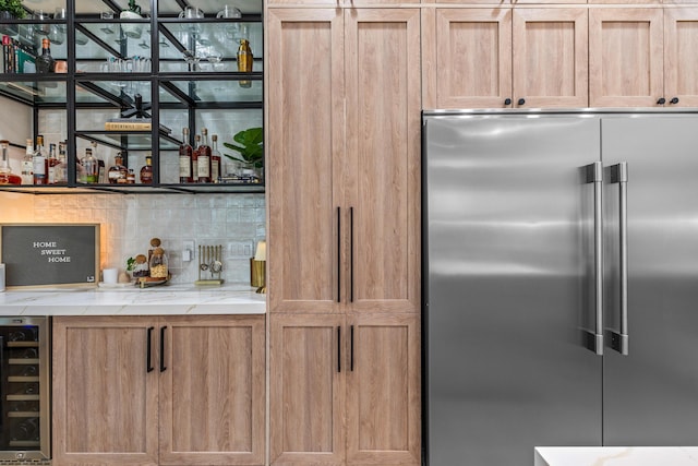 kitchen with light stone counters, built in refrigerator, beverage cooler, and backsplash