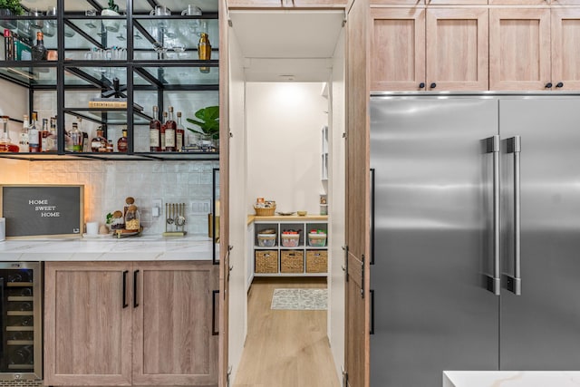 kitchen featuring decorative backsplash, stainless steel built in fridge, wine cooler, and light hardwood / wood-style flooring