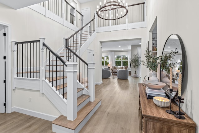 stairs with hardwood / wood-style flooring, a towering ceiling, and an inviting chandelier