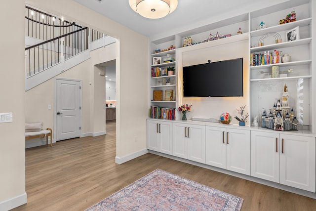 living room with built in features and light wood-type flooring