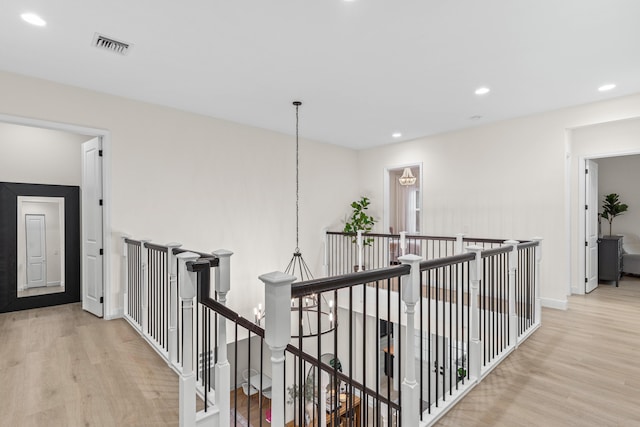 hallway featuring a chandelier and light hardwood / wood-style flooring