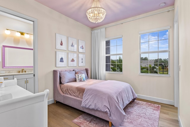 bedroom with ensuite bathroom, a chandelier, and light hardwood / wood-style floors