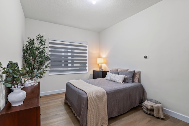 bedroom featuring light hardwood / wood-style floors and a textured ceiling