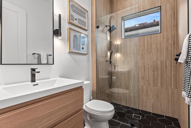 bathroom with tiled shower, vanity, toilet, and tile patterned floors