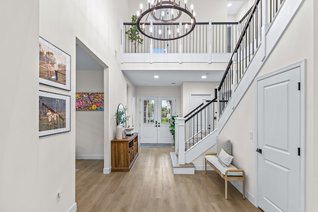 foyer featuring a notable chandelier, light hardwood / wood-style flooring, french doors, and a high ceiling