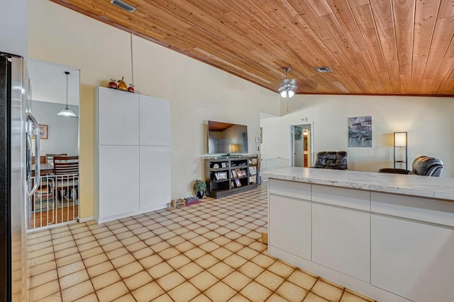 kitchen with vaulted ceiling, pendant lighting, stainless steel refrigerator, white cabinets, and wooden ceiling