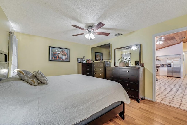 bedroom featuring a textured ceiling, stainless steel fridge, ceiling fan, and light hardwood / wood-style floors