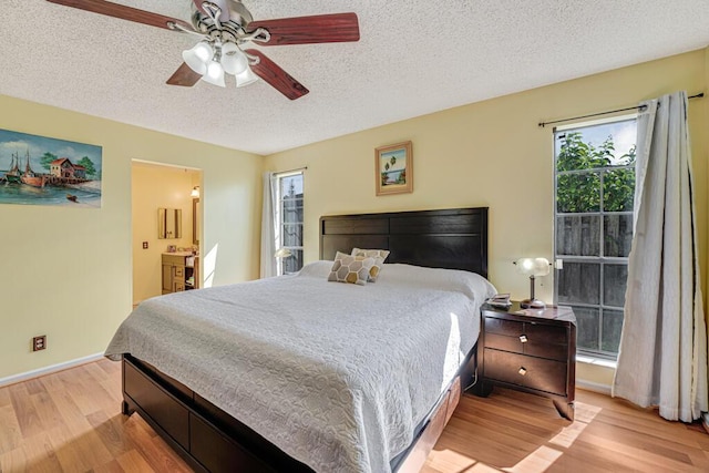 bedroom with a textured ceiling, ensuite bathroom, ceiling fan, and light wood-type flooring