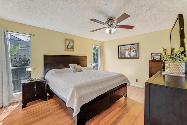 bedroom featuring ceiling fan, light hardwood / wood-style flooring, and a textured ceiling