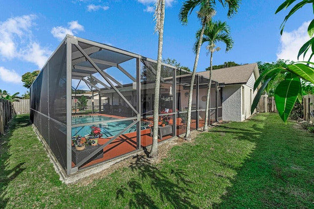 rear view of house with a fenced in pool, a lanai, and a lawn