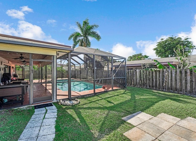 view of yard with a fenced in pool, ceiling fan, glass enclosure, and a patio