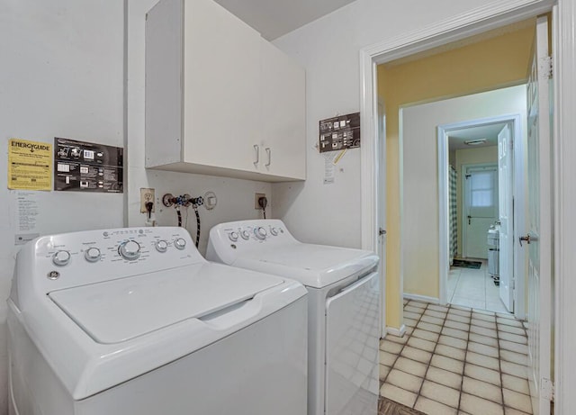 clothes washing area featuring cabinets, light tile patterned floors, and washing machine and clothes dryer